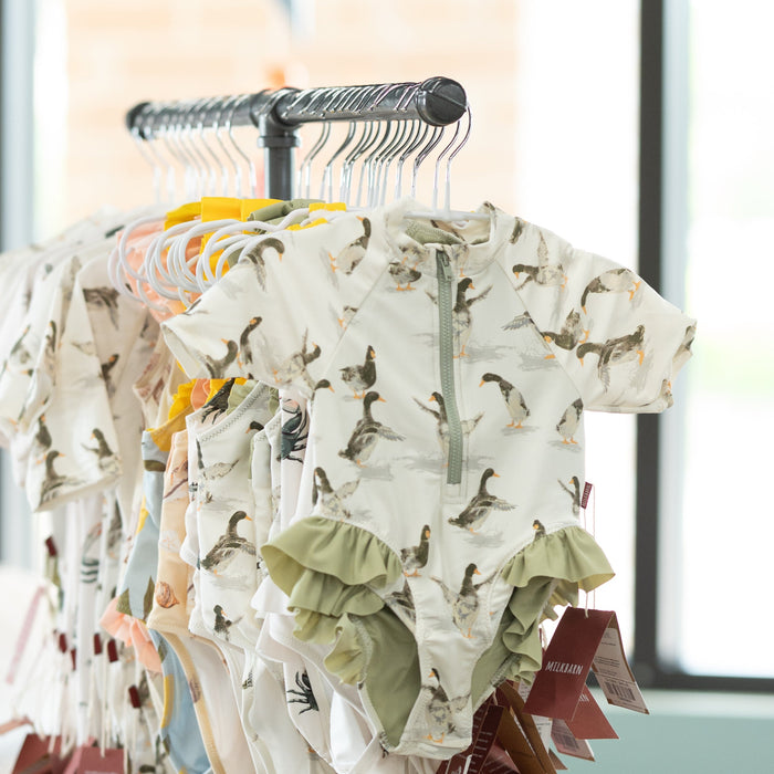 Clothing rack with patterned baby toddle swimwear in a room with large windows
