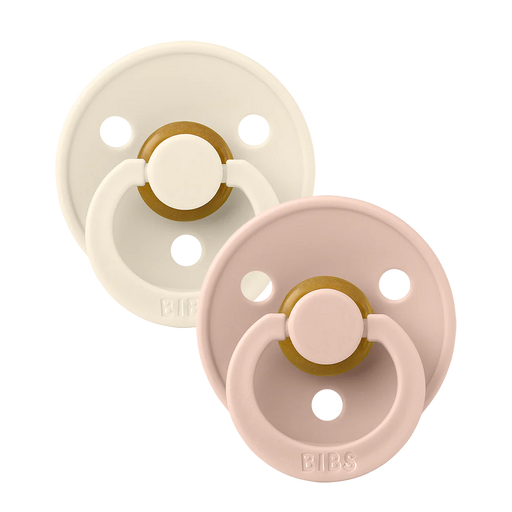 Two BIBS round pacifiers shown together, featuring an ivory pacifier and a blush pacifier with round shields