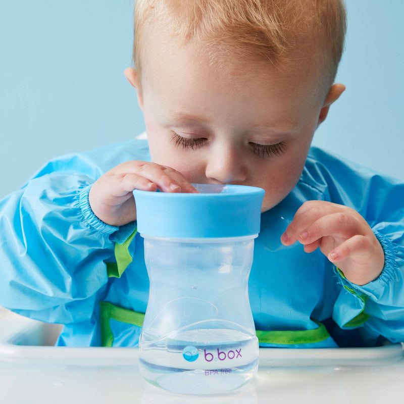 Child drinking from a blue sippy cup with 'bbox' branding against a light blue background