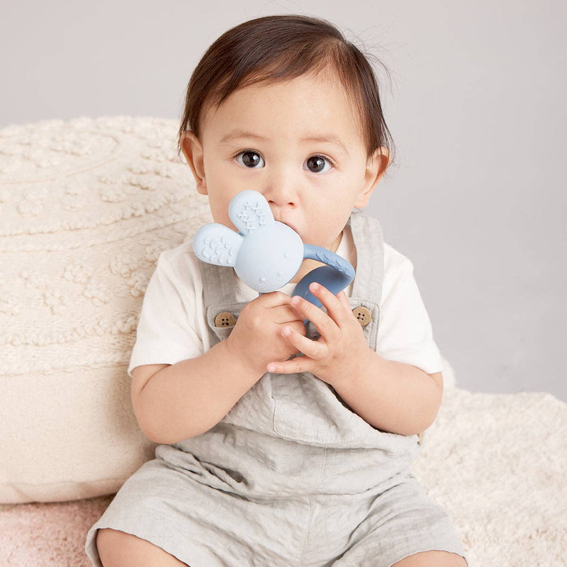 Baby holding a blue toy with a neutral background