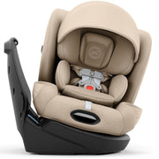 A baby car seat in beige fabric with a black base, shown at an angle on a white background.