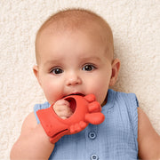Baby holding and chewing on the Bitzy Grip teether during teething