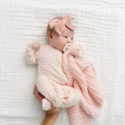 Newborn in the Lou Lou & Co Harper pink striped footie and pink bow, cuddling a pink knit blanket
