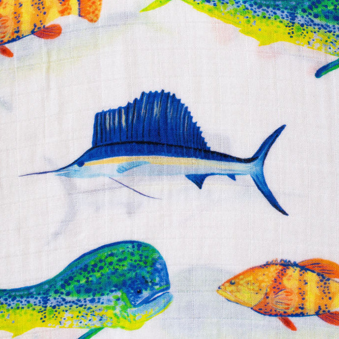 A close-up of a fabric featuring a colorful print of tropical fish, including a prominent blue sailfish in the center, with other fish in yellow, orange, and green on a white background.