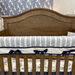 Wooden crib with striped crib sheet and decorative bows in a nursery setting.