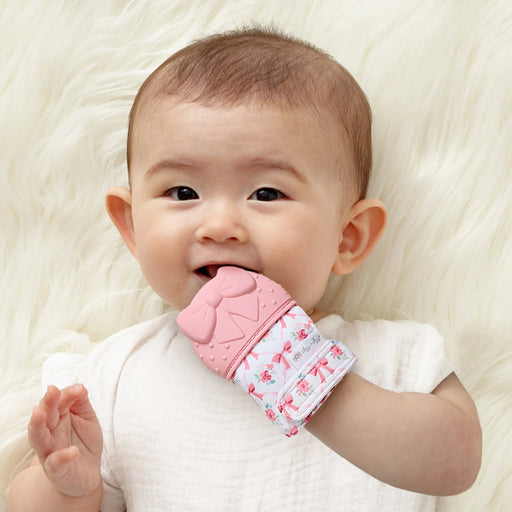 Baby wearing and chewing on the Itzy Ritzy silicone teether mitt during teething
