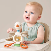 Baby sitting in a high chair with a toy, looking surprised or excited.