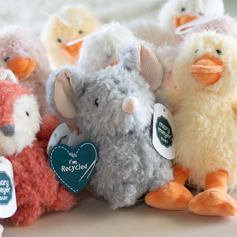 Plush toys including a fox, rabbit, and duck on a light surface with a blurred background