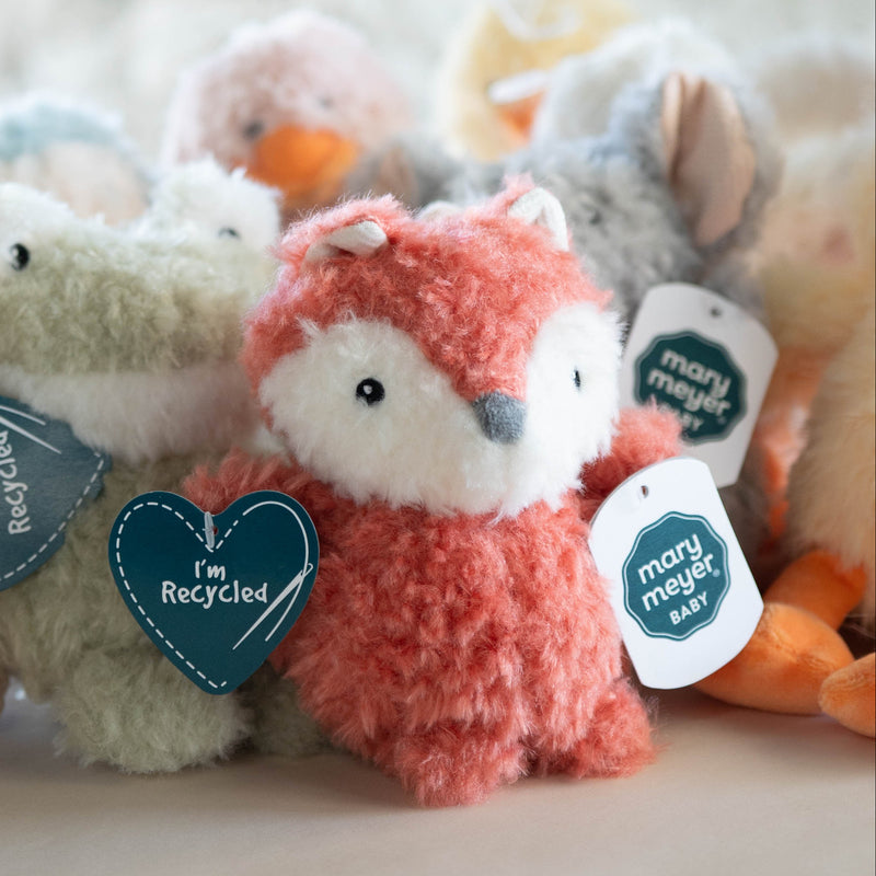 Collection of small plush toys with heart-shaped tags on a light surface.