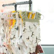 Children's swimwear with coastal prints on hangers against a neutral background