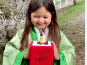 Child holding a red Toniebox with the Mulan Tonie outdoors, lifestyle scene