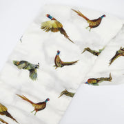 Flatlay of Saltwater Swaddles Pheasant and Quail bamboo cotton swaddle featuring hand-painted birds in flight on a white background