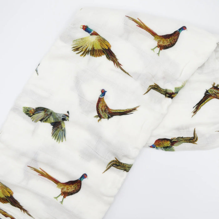 Flatlay of Saltwater Swaddles Pheasant and Quail bamboo cotton swaddle featuring hand-painted birds in flight on a white background