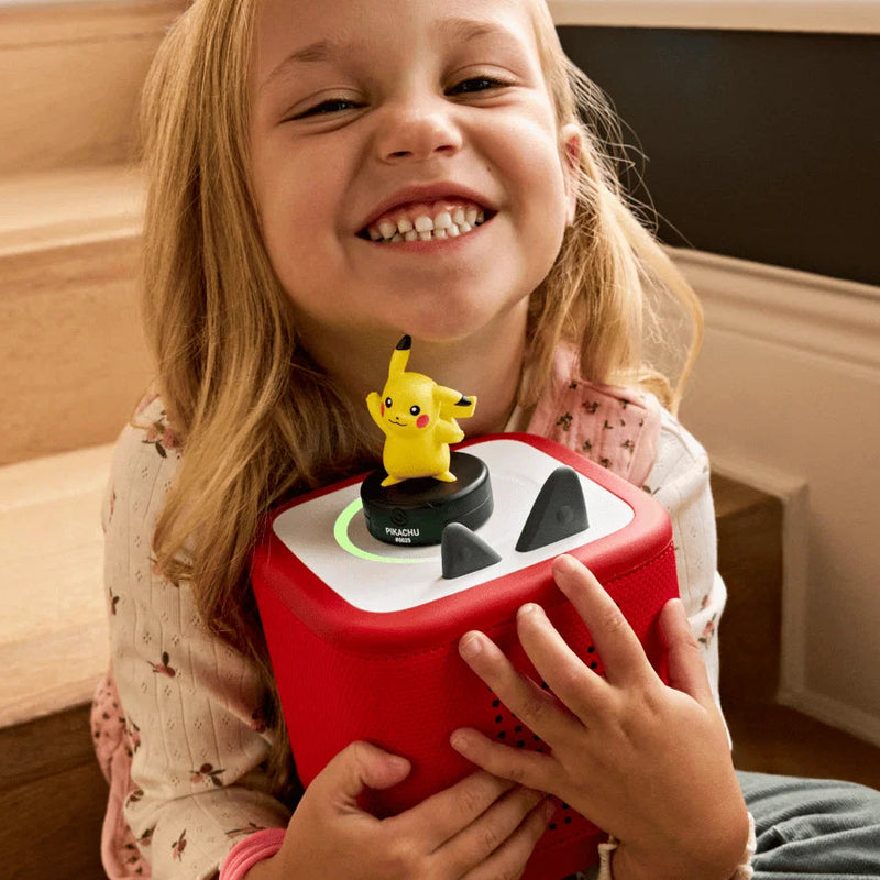 Child holding a red toy with a character on top, smiling.
