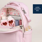 Open backpack diaper bag filled with baby essentials including bottles, shoes, and accessories