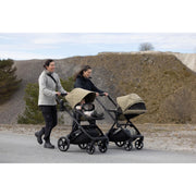 Two parents walking with Thule Charm strollers outdoors