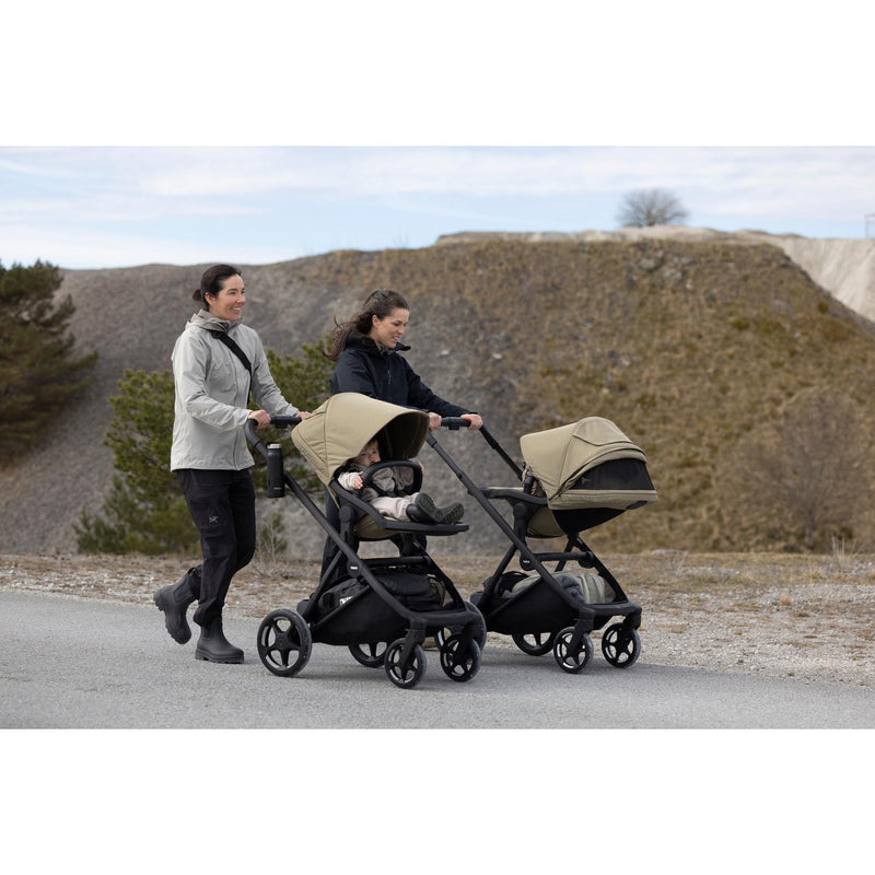 Two parents walking with Thule Charm strollers outdoors