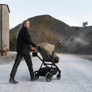 Parent pushing Thule Charm stroller on a gravel road