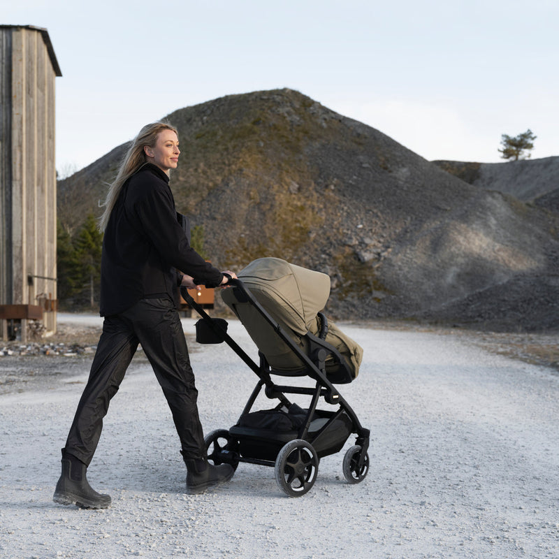 Parent pushing Thule Charm stroller on a gravel road