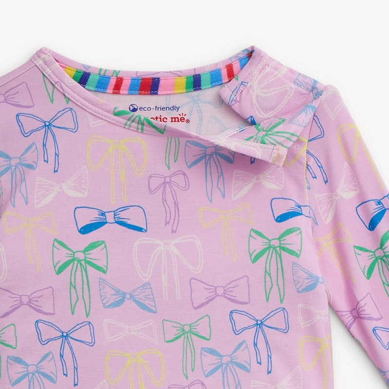 Pink shirt with colorful bow pattern and rainbow collar on a white background