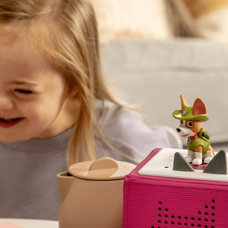 Child playing with a toy tea set and figurine, smiling.
