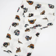 A white muslin baby blanket or scarf featuring an all-over print of painted wild turkeys in brown, black, and orange, folded neatly on a white background.