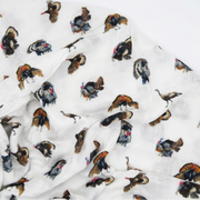 White lightweight fabric printed with a scattered pattern of wild turkey birds in brown, black, gray, and red tones, draped against a plain white background.