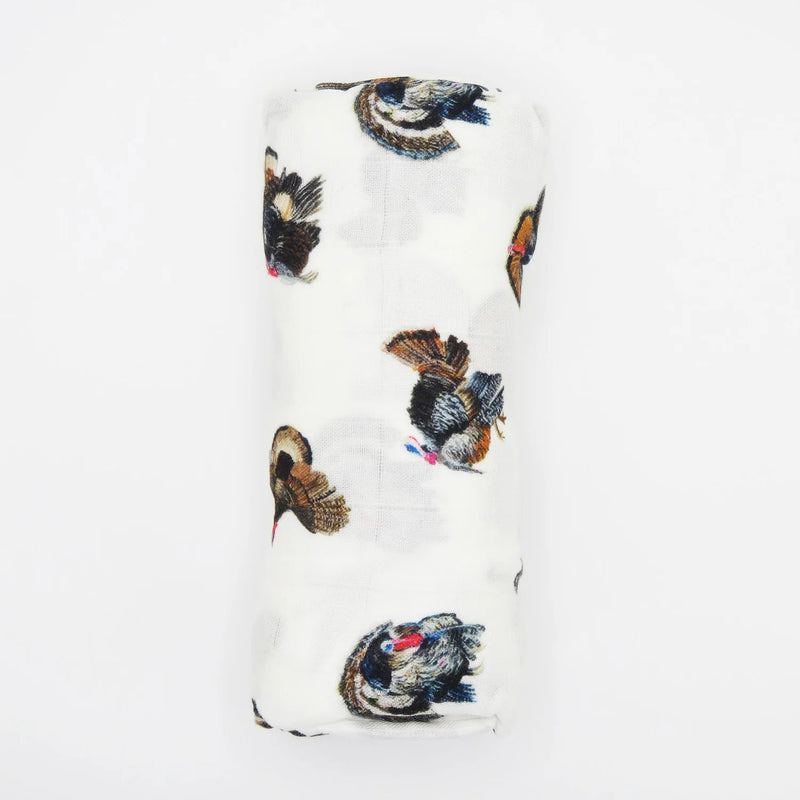 baby blanket featuring a scattered print of wild turkeys in black, brown, and blue, with a small red comb detail, shown on a plain white background.