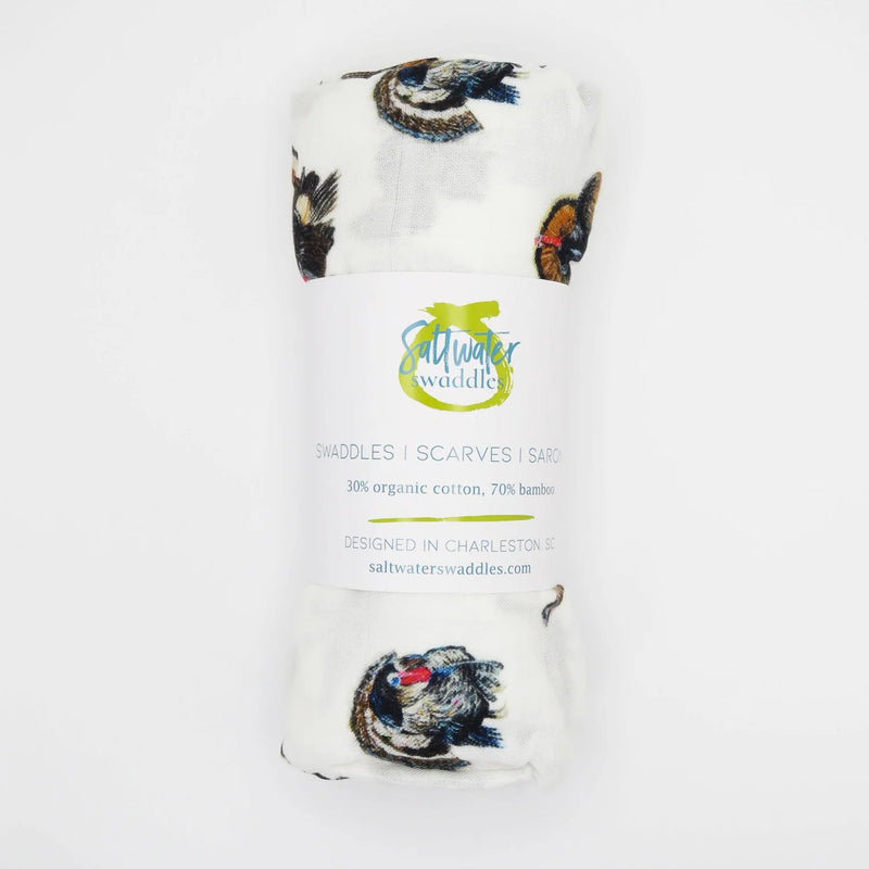 A rolled white baby scarf or shawl with a butterfly print, wrapped in a paper band that reads 'Muir Waterdale' and 'BATTLES | SCARVES | SASHES'.
