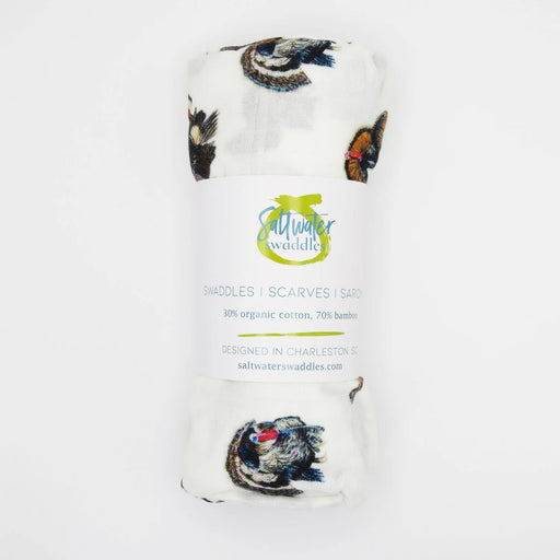A rolled white baby scarf or shawl with a butterfly print, wrapped in a paper band that reads 'Muir Waterdale' and 'BATTLES | SCARVES | SASHES'.