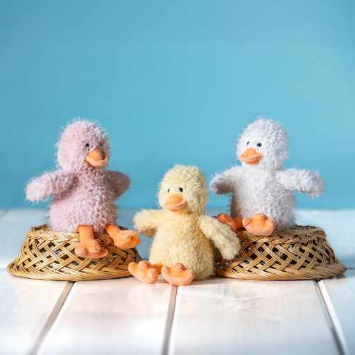 Assorted pastel plush ducks displayed together on a small bench against a blue background