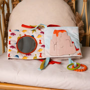 Book opened on a bed showing a round baby-safe mirror and a volcano flap scene.