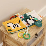 Open soft activity book showing zebra and toucan jungle pages with textures.