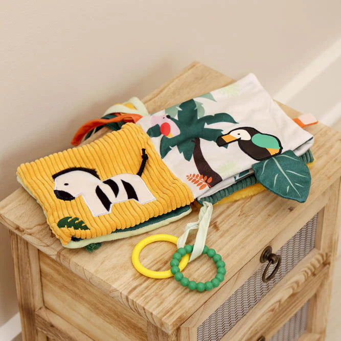 Open soft activity book showing zebra and toucan jungle pages with textures.