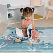 Child interacting with the open soft book on a play mat.