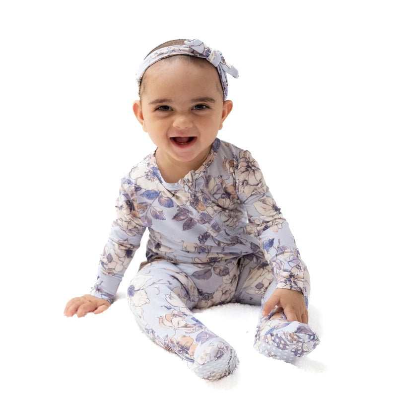 Baby wearing Woodrose Peri ruffle back footie, sitting and smiling