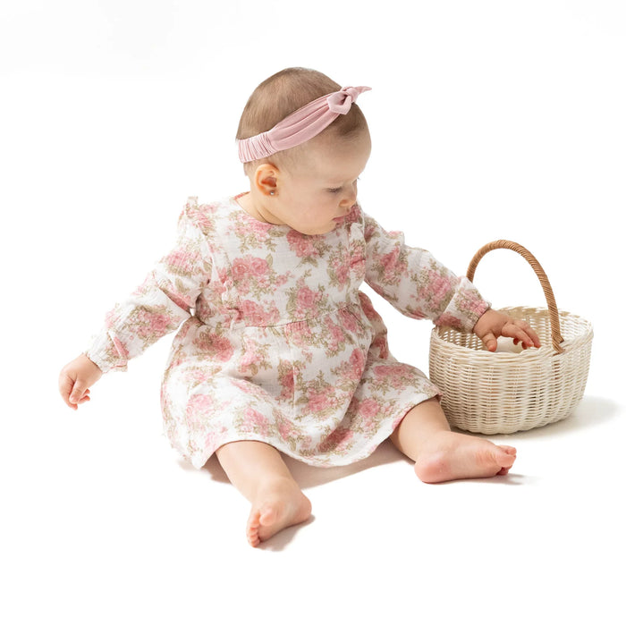 Baby wearing Heirloom Bouquets ruffle long-sleeve bubble with skirt, sitting and playing with a basket.