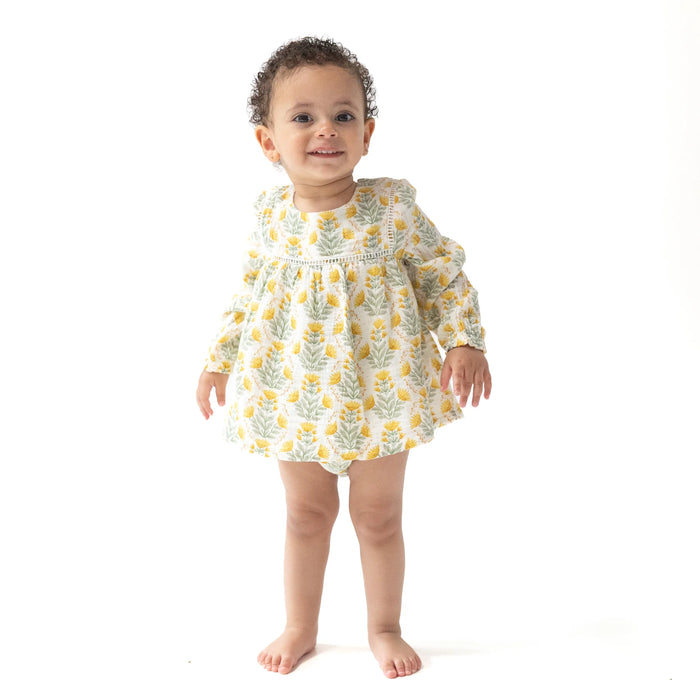 Baby wearing the Winter Dandelions puffed sleeve bubble dress, standing and smiling