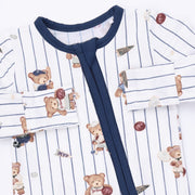 A close-up of a baby long-sleeve pajama top featuring a white base with thin navy blue pinstripes, a solid navy collar and front tie closure, and an all-over print of teddy bears in baseball and sports outfits.