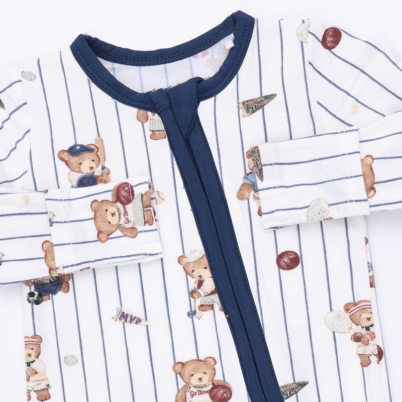 A close-up of a baby long-sleeve pajama top featuring a white base with thin navy blue pinstripes, a solid navy collar and front tie closure, and an all-over print of teddy bears in baseball and sports outfits.