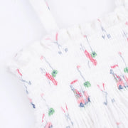 White smocked fabric garment with a delicate multicolor pattern of pink, green, and blue embroidered details, shown in a close-up view.