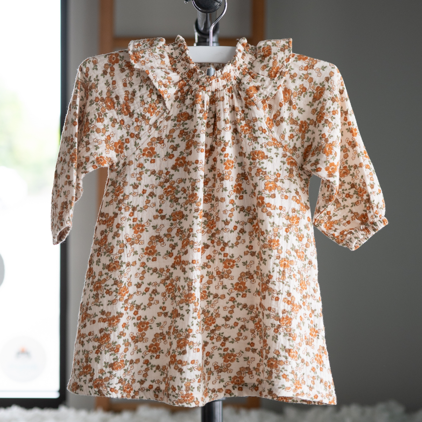 Baby wearing a brown and white striped long sleeve pant romper on a white background