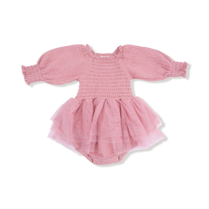 A long sleeve baby bubble outfit in a soft rose pink color. The bodice features stretchy smocking, the sleeves are made of lightweight muslin with elastic cuffs, and the bottom is attached to a layered pink tulle tutu skirt. The romper includes built in bloomers with snaps at the bottom.