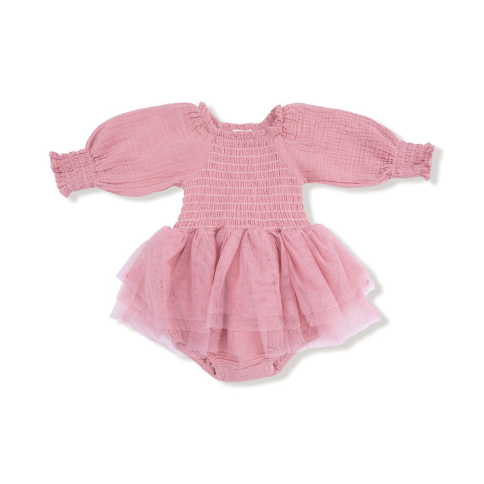 A long sleeve baby bubble outfit in a soft rose pink color. The bodice features stretchy smocking, the sleeves are made of lightweight muslin with elastic cuffs, and the bottom is attached to a layered pink tulle tutu skirt. The romper includes built in bloomers with snaps at the bottom.