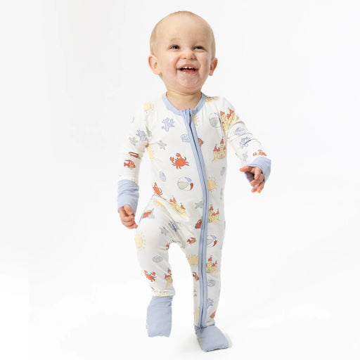 Baby wearing a colorful onesie with sea creature pattern on a white background