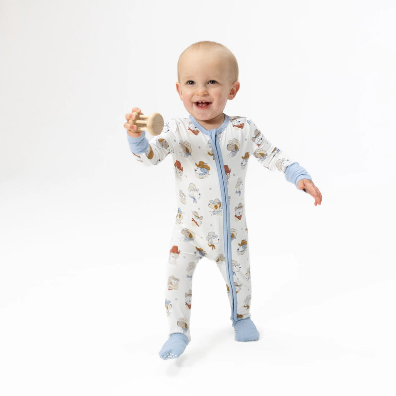 Baby wearing a cowboy dog patterned onesie on a white background