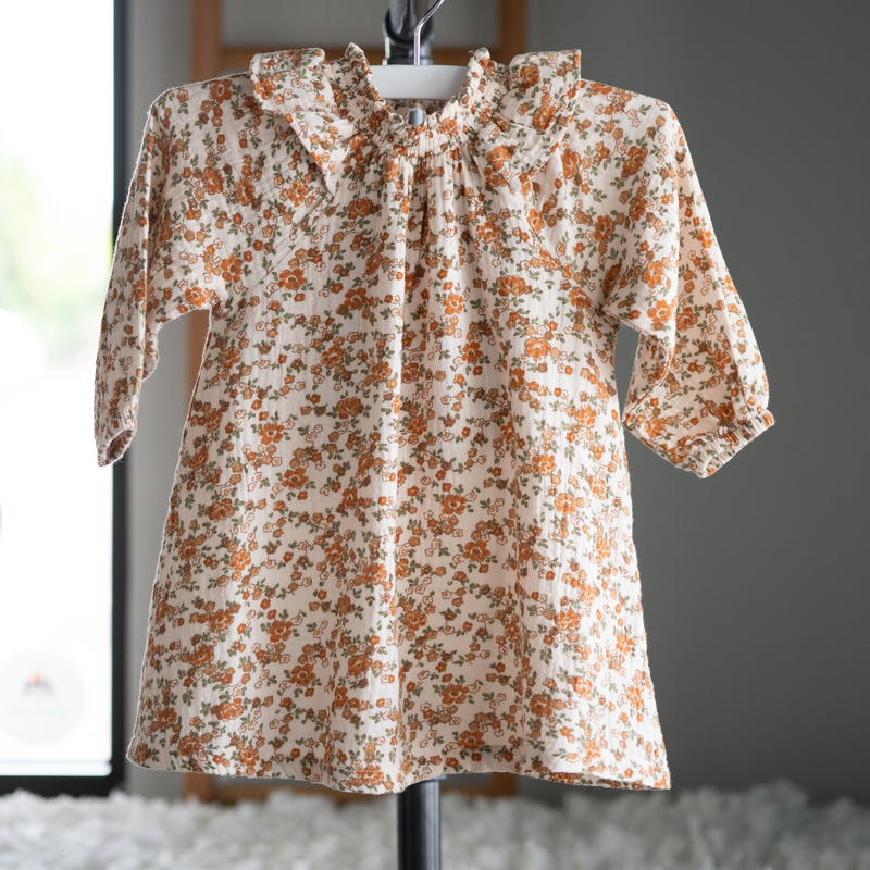 Floral baby toddler muslin dress on a hanger against a neutral background