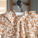 Floral dress elastic ruffled collar with orange flowers on a hanger against a blurred background