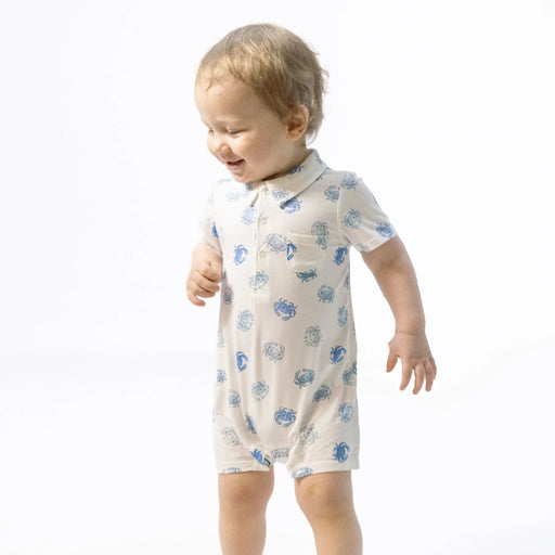 Baby wearing a white romper with blue patterns on a white background