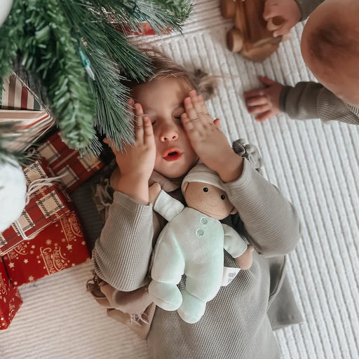 Child with a toy under a Christmas tree with presents underneath